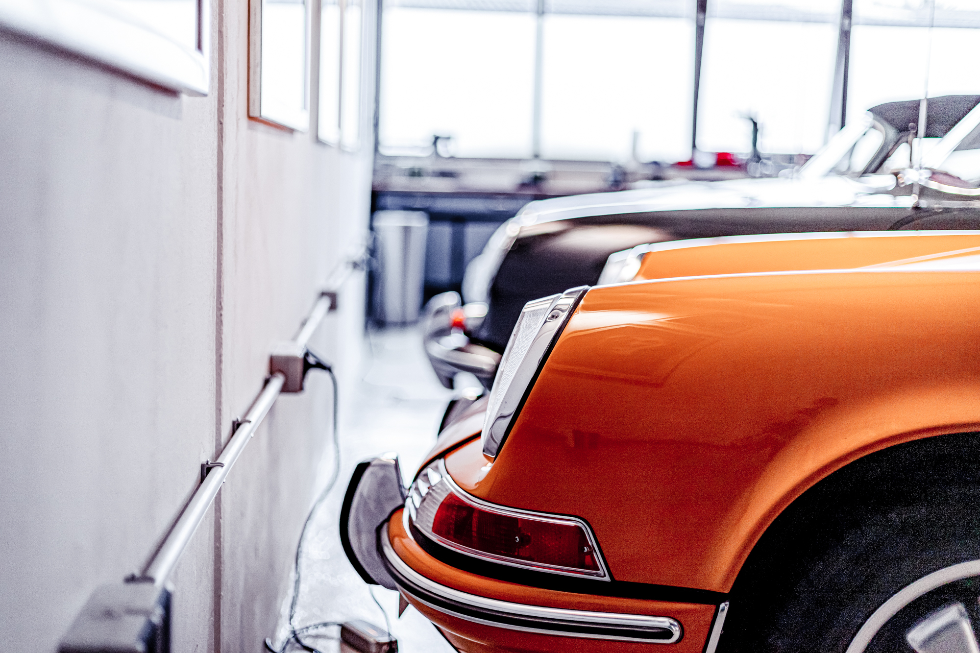 Ein orangener Oldtimer steht nahe an der Wand einer Garage.